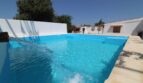 Großer Pool mit Wasserfall der Finca in Son Ferriol, umgeben von weißen Mauern und mediterranem Garten.