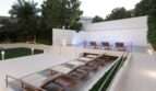 Modern pool terrace with wooden loungers, white stone walls and tropical plants in Palma de Mallorca