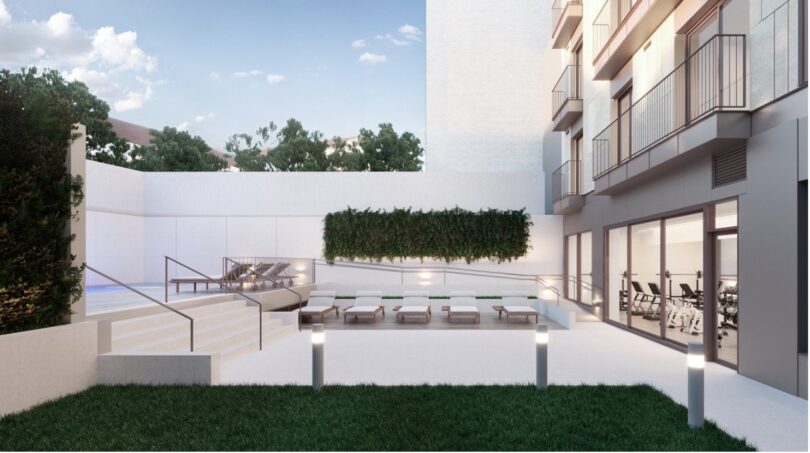 Modern outdoor area with pool, lounge chairs, green plant wall and fitness room of a penthouse in Palma