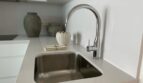Moderne weiße Küche mit Unterbau-Edelstahlspüle, Chrom-Einhebelmischer und eleganter Deko in Palma de Mallorca