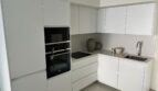Moderne weiße L-Küche mit Siemens Einbaugeräten, Induktionskochfeld und Granitarbeitsplatte in Palma-Apartment