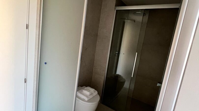 Modernes Badezimmer mit Milchglasabtrennung, Wandhänge-WC und Glasdusche in Palma-Luxusapartment