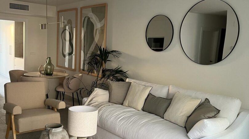 Helles Wohnzimmer mit weißem Sofa, Rundspiegeln und modernem Couchtisch in Palma de Mallorca