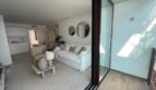 Helles Wohnzimmer mit weißem Sofa, Glasschiebetür und offener Küche in Luxus-Apartment, Palma de Mallorca