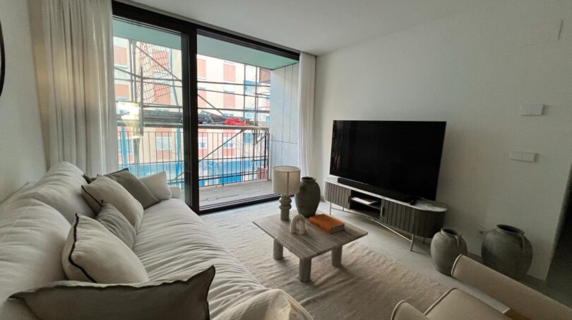 Helles Wohnzimmer mit großem Flachbildschirm, Balkonzugang und modernem Sofa in Palma de Mallorca