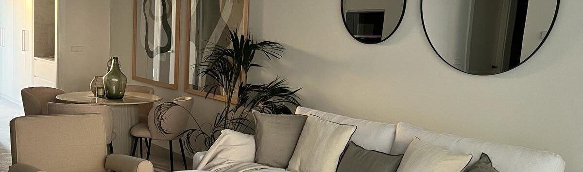 Helles Wohnzimmer mit weißem Sofa, Rundspiegeln und elegantem Couchtisch in Luxusapartment Palma