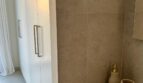Modernes Badezimmer mit Steinoptik-Fliesen, weißem Waschtisch und goldenen Accessoires in Luxus-Apartment Palma