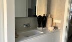 Modernes Badezimmer mit weißem Waschtisch, Wandarmatur und dekorativen Akzenten in luxuriösem Apartment Palma