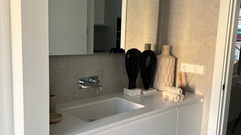 Modernes Badezimmer mit weißem Waschtisch, Wandarmatur und dekorativen Akzenten in luxuriösem Apartment Palma