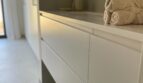 Modernes Luxusbad mit weißem Waschtischunterschrank, Betonoptik-Wand und gefalteten Handtüchern in Palma de Mallorca
