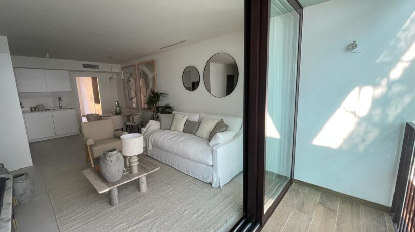 Helles Wohnzimmer mit weißem Sofa, Glasschiebetür zur Terrasse und modernem Dekor im Luxusapartment Palma de Mallorca