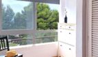 Heller Eingangsbereich mit Schuhschrank, schwarzem Stuhl und großem Fenster mit Grünblick in Palma de Mallorca