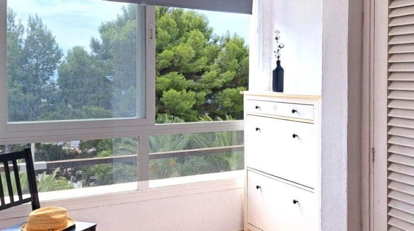Heller Eingangsbereich mit Schuhschrank, schwarzem Stuhl und großem Fenster mit Grünblick in Palma de Mallorca