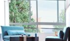 Helles Wohnzimmer mit türkisfarbenen Sofas, Panoramafenstern und Blick auf Palmen in Palma de Mallorca.