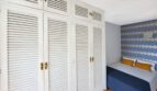 Schlafzimmer mit weißem Einbauschrank, blauer Bettwäsche und gemusterter Tapete in Strandwohnung Palma de Mallorca