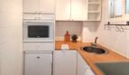Kompakte weiße Küche mit Einbauofen, Mikrowelle, Rundspüle und Waschmaschine in strandnaher Wohnung in Palma de Mallorca.