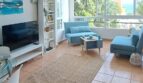Helles Wohnzimmer mit blauen Möbeln, Flachbild-TV und Panoramafenster mit Meerblick in Palma de Mallorca.