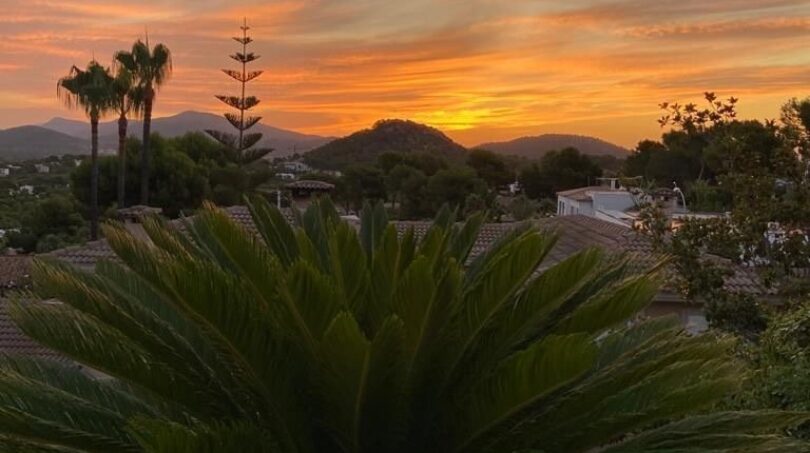 Espectacular puesta de sol sobre Santa Ponça con palmeras, villas y montañas – vista panorámica de la villa moderna.
