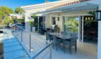 Moderna terraza de la villa en Santa Ponça con área de comedor al aire libre, toldo y barandilla de cristal.