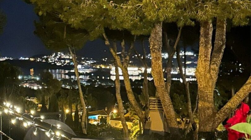 Balcón iluminado por la noche con vistas panorámicas a las luces de Santa Ponça y la costa marina.