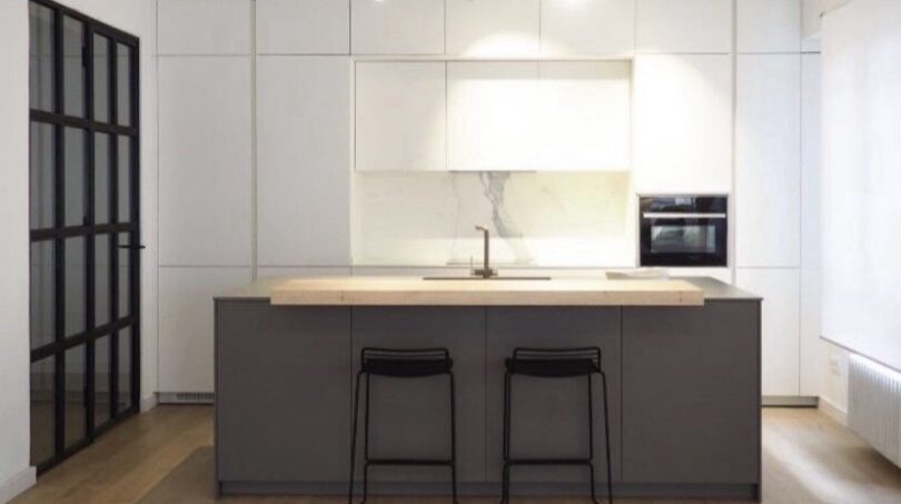 Moderne Küche mit Kochinsel, weißen Hochschränken und Barhockern in Palma de Mallorca Wohnung