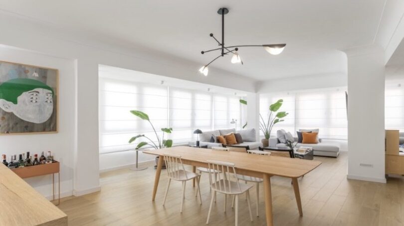 Helles Wohn-Esszimmer mit Holztisch, weißen Stühlen, modernem Kronleuchter und großen Fenstern in Palma