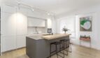 Moderne offene Küche mit Kochinsel, weißen Fronten und Barhocker in top modernisierter Wohnung in Palma