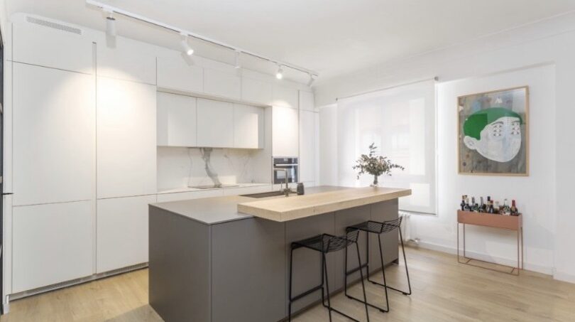 Moderne offene Küche mit Kochinsel, weißen Fronten und Barhocker in top modernisierter Wohnung in Palma