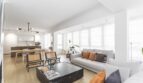 Helles Wohnzimmer mit grauem Sofa, Marmor-Couchtisch und offener Küche in modernisierter Palma-Wohnung.