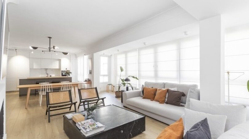 Helles Wohnzimmer mit grauem Sofa, Marmor-Couchtisch und offener Küche in modernisierter Palma-Wohnung.