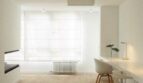Helles minimalistisches Arbeitszimmer mit weißem Schreibtisch, modernem Stuhl und Holzboden in Palma-Wohnung.