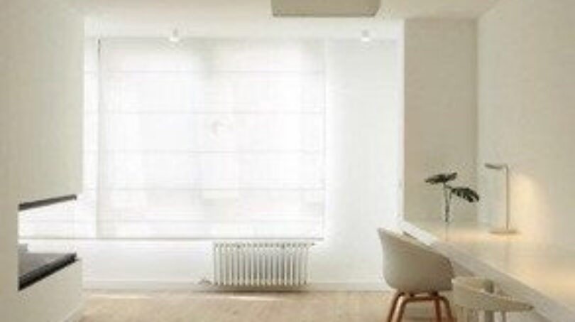 Helles minimalistisches Arbeitszimmer mit weißem Schreibtisch, modernem Stuhl und Holzboden in Palma-Wohnung.
