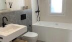 Modernes Badezimmer mit schwarzen Armaturen, Einbauwanne, Wandhänge-WC und Holz-Waschtisch in Palma-Wohnung.