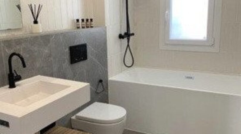 Modernes Badezimmer mit schwarzen Armaturen, Einbauwanne, Wandhänge-WC und Holz-Waschtisch in Palma-Wohnung.