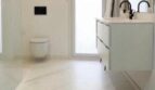 Modernes weißes Badezimmer mit Marmoroptik-Fliesen, schwebendem Waschtisch und wandhängendem WC in Palma-Wohnung.