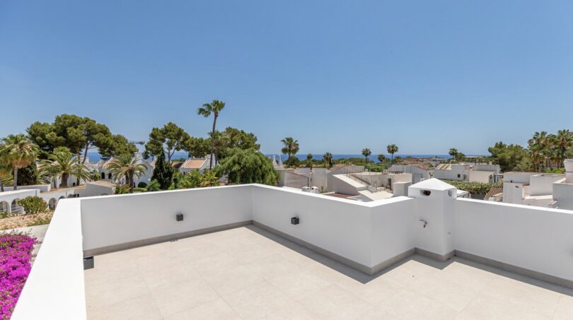 Helle Dachterrasse der Traumvilla in Sol de Mallorca mit Meerblick, Palmen und weißen Nachbarhäusern.