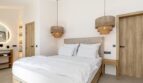 Helles Schlafzimmer der Mallorca-Villa mit Doppelbett, Holzelementen und stilvollen Rattanlampen