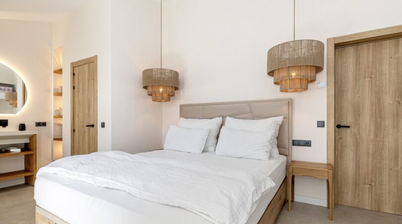 Helles Schlafzimmer der Mallorca-Villa mit Doppelbett, Holzelementen und stilvollen Rattanlampen