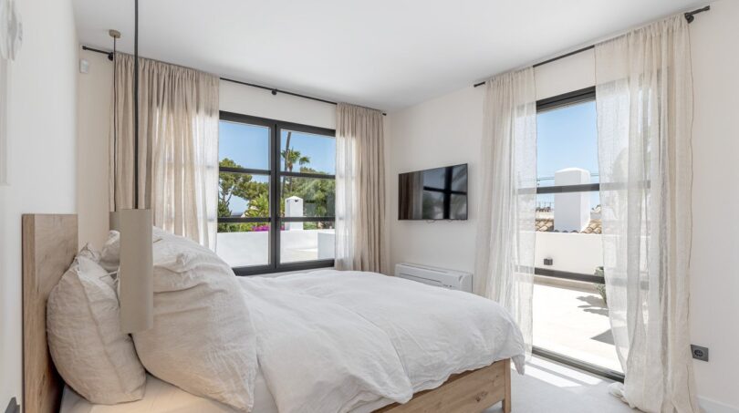 Helles Schlafzimmer der Traumvilla mit Doppelbett, Meerblick-Terrasse und eleganten Leinengardinen