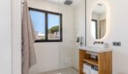 Modernes Badezimmer der Villa mit Glasdusche, Holzwaschtisch und beleuchtetem Spiegel in Sol de Mallorca
