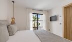 Helles Schlafzimmer der Traumvilla in Sol de Mallorca mit Doppelbett, Pendellampe und Terrassenzugang zum Pool.