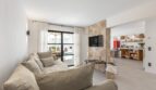 Helles Wohnzimmer der Villa mit Natursteinwand, TV, Sofa und Zugang zur Poolterrasse in Sol de Mallorca