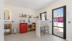 Helle Kitchenette mit rotem Minikühlschrank, Bartheke und Zugang zur sonnigen Terrasse der Mallorca-Villa.