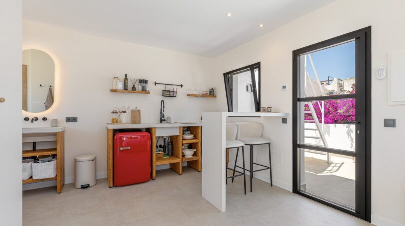 Helle Kitchenette mit rotem Minikühlschrank, Bartheke und Zugang zur sonnigen Terrasse der Mallorca-Villa.