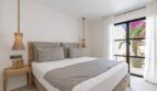 Helles Schlafzimmer der Traumvilla in Sol de Mallorca mit Doppelbett, Holzmöbeln und Balkon mit Bougainvillea.