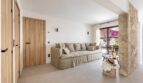 Helles Wohnzimmer der Traumvilla mit Leinensofa, Natursteinwand und Blick auf sonnige Terrasse in Sol de Mallorca.