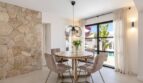 Elegantes Esszimmer der Traumvilla in Sol de Mallorca mit Natursteinwand, Rundtisch und Poolblick.