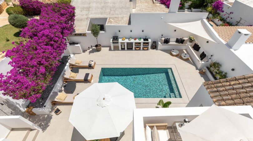 Luftaufnahme: Pool mit Sonnenliegen, Außenküche und Bougainvillea-Blüten der Villa in Sol de Mallorca