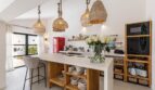 Moderne Küche der Traumvilla mit Kochinsel, Holzregalen und Rattanlampen in Sol de Mallorca