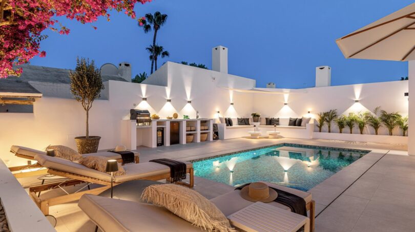 Beleuchteter Außenpool mit Loungebereich, Außenküche und weißen Wänden der Traumvilla in Sol de Mallorca